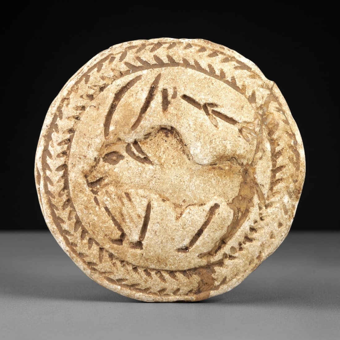 Ancient Stone Double Convex Relic - Near Eastern Animal Figurine, 80AL: Crafted from stone, this double convex relic features incised animal motifs-including a horned quadruped and a leaping hare-across its two faces, framed by a continuous braided border. Attributed to a
