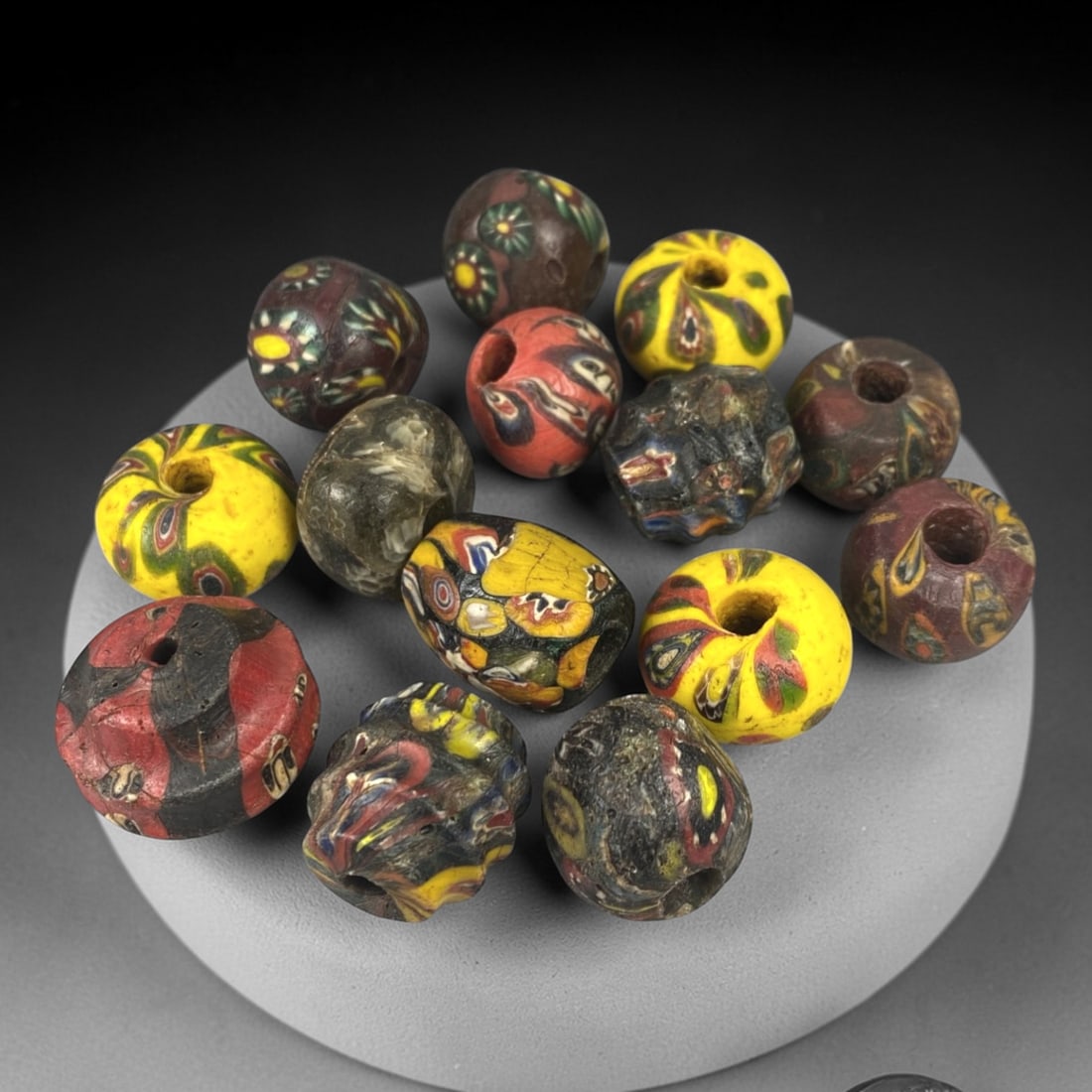 Antique Venetian Glass Beads - 14 Pieces, 15ZT: Crafted from hand-worked glass, this set of 14 antique Venetian beads displays a vibrant array of polychrome mosaic and cane-work patterns, characteristic of 19th-century European trade bead productio