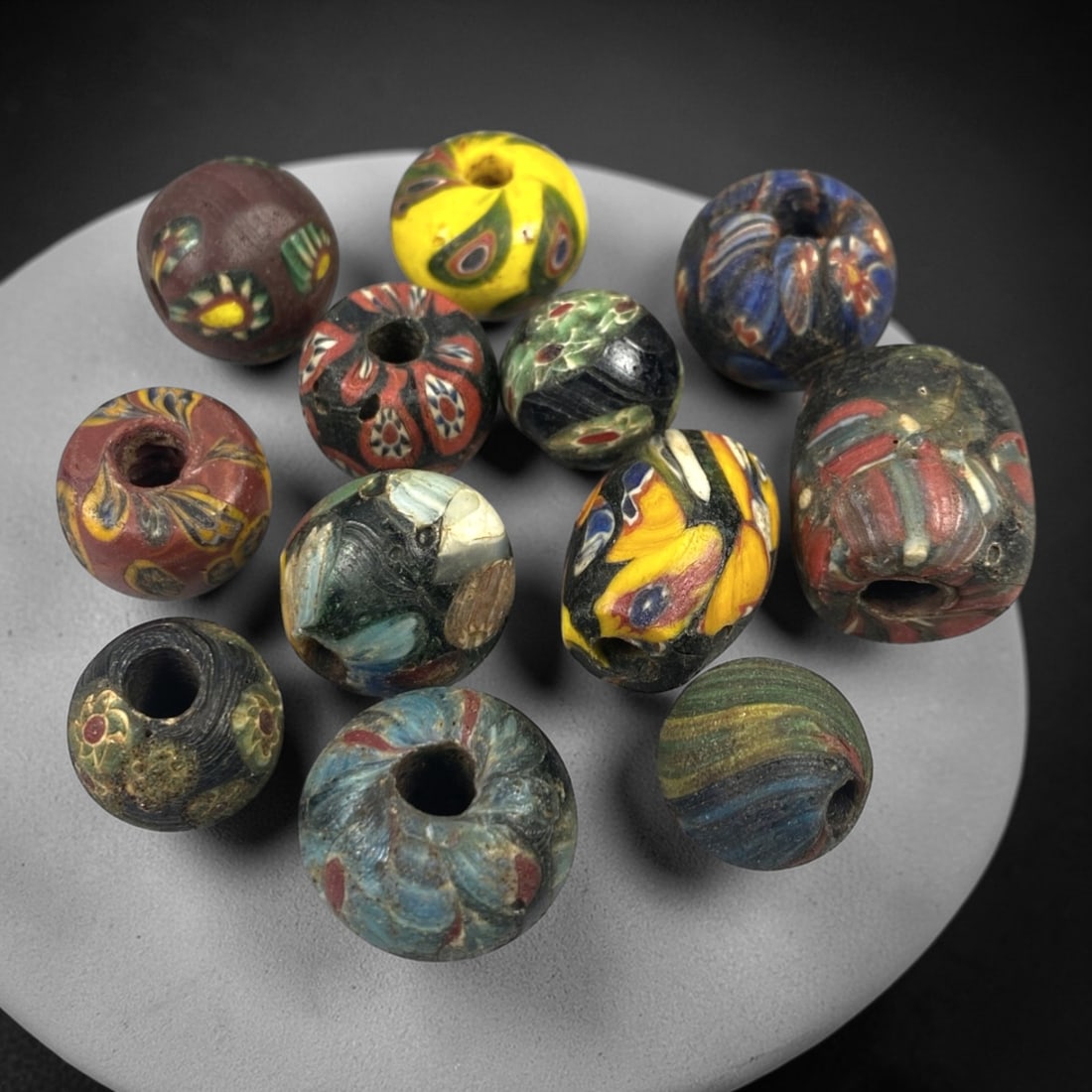 Antique Venetian Glass Beads - 12 Pieces, 54FX: This set of 12 antique Venetian glass beads features diverse hand-formed shapes including spherical and slightly irregular forms, crafted from polychrome glass with intricate mosaic and cane-work patt