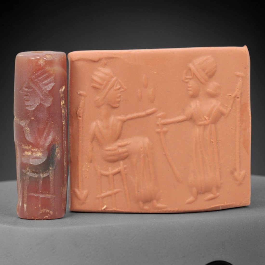 Ancient Carnelian Cylinder Seal - Mesopotamian Figural Ritual Scene, 73ZS: Carved from richly hued carnelian, this ancient Mesopotamian cylinder seal features a refined linear relief composition of two human figures in ritual interaction-one seated on a stool and gesturing,
