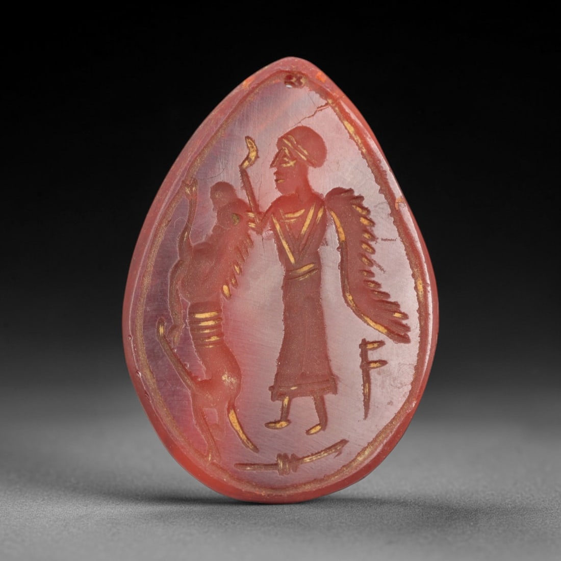 Ancient Carnelian Intaglio Amulet Pendant - Near Eastern Winged Deity & Mythical Creature, 46ZS: Carved from a rich, translucent reddish-brown carnelian, this teardrop-shaped intaglio amulet pendant depicts a standing winged deity alongside a rearing mythical creature, likely a griffin or sphinx.