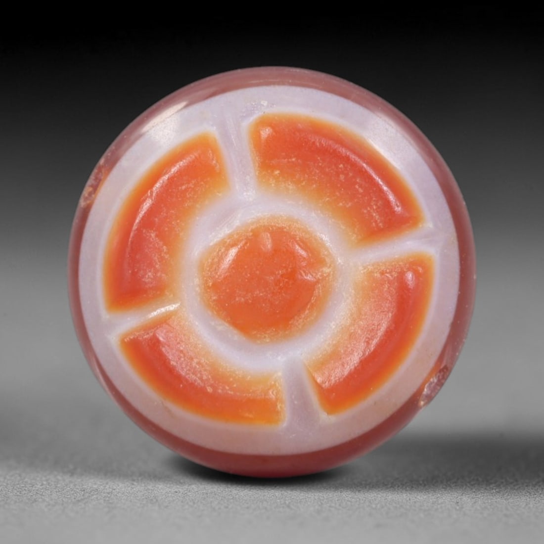 Antique Agate Wheel Bead - Central Asian Gemstone Pendant, 16AR: Carved from banded agate with a soft pinkish base and vibrant orange-white concentric banding, this bead features a symmetrical wheel motif with a central circular core and four curved segmental spoke