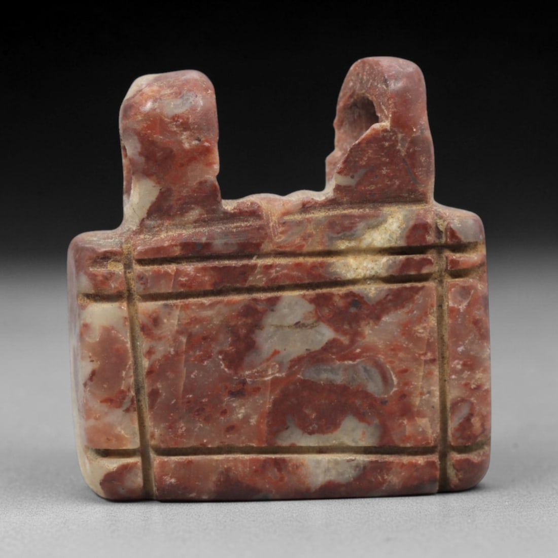 Ancient Near Eastern Variegated Red Stone Shrine Amulet - Carved Pendant Figure, 43ZV: This amulet is carved from a striking variegated red and white stone, likely brecciated jasper or travertine, with incised linear details defining its stylized shrine form. The piece features a rectan