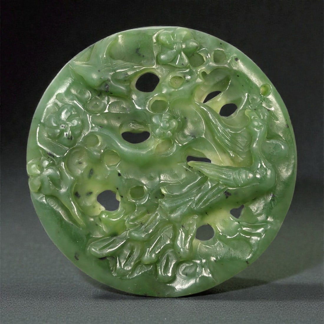A Chinese Green Nephrite Jade Openwork Pendant Carved with Birds and Phoenix, 20th Century, 45FA: Carved from translucent spinach-green nephrite jade with lighter apple-green areas and scattered dark mineral inclusions, the pendant is of circular disc form and worked in openwork relief on one face