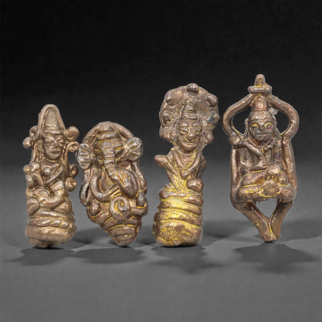 Four Thai Gilt-Copper Buddhist and Hindu Miniature Figures, 20th Century, 19FM: Cast from copper with residual gilding, the set comprises four miniature votive figures representing Hindu and Buddhist iconography: a seated deity with a tiered headdress, an elephant-headed figure c