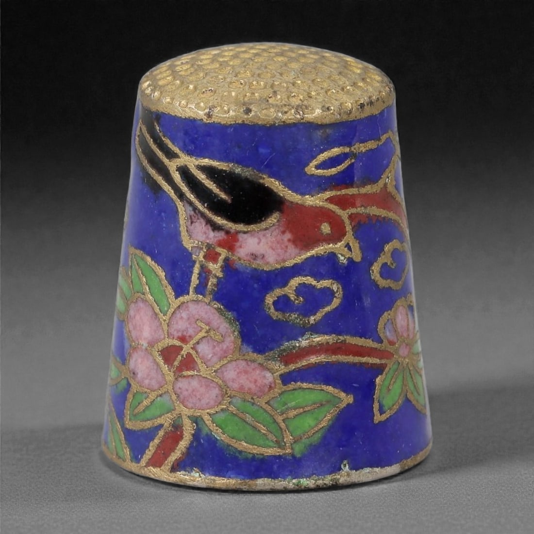 A Chinese Cloisonne Enamel Thimble, 20th Century, 12FH: Formed as a tapering cylindrical thimble with a domed top, the object is constructed over a metal core and decorated in cloisonne enamel on a deep cobalt blue ground, the surface embellished with a fl