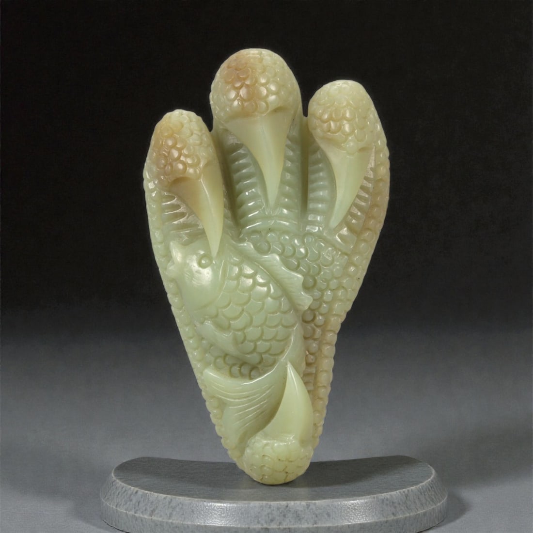A Chinese Nephrite Jade Eagle Claw and Fish Ornament, 20th Century, 9FC: Carved from pale celadon Hetian nephrite jade with areas of translucent polish and minor natural inclusions, the object is worked in the form of an eagle's talon grasping a fish. The composition is ve