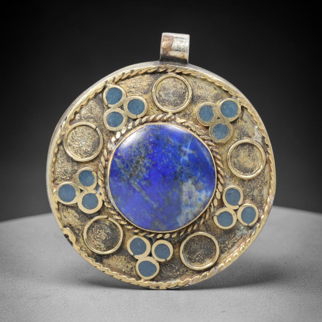 Vintage Himalayan Lapis Lazuli Brass Amulet Pendant, 20th Century, 5cm, 73ZP: This vintage circular pendant is a fine example of 20th-century Himalayan tribal jewelry, crafted from brass with a central lapis lazuli cabochon. The design features a large, deep blue lapis stone at