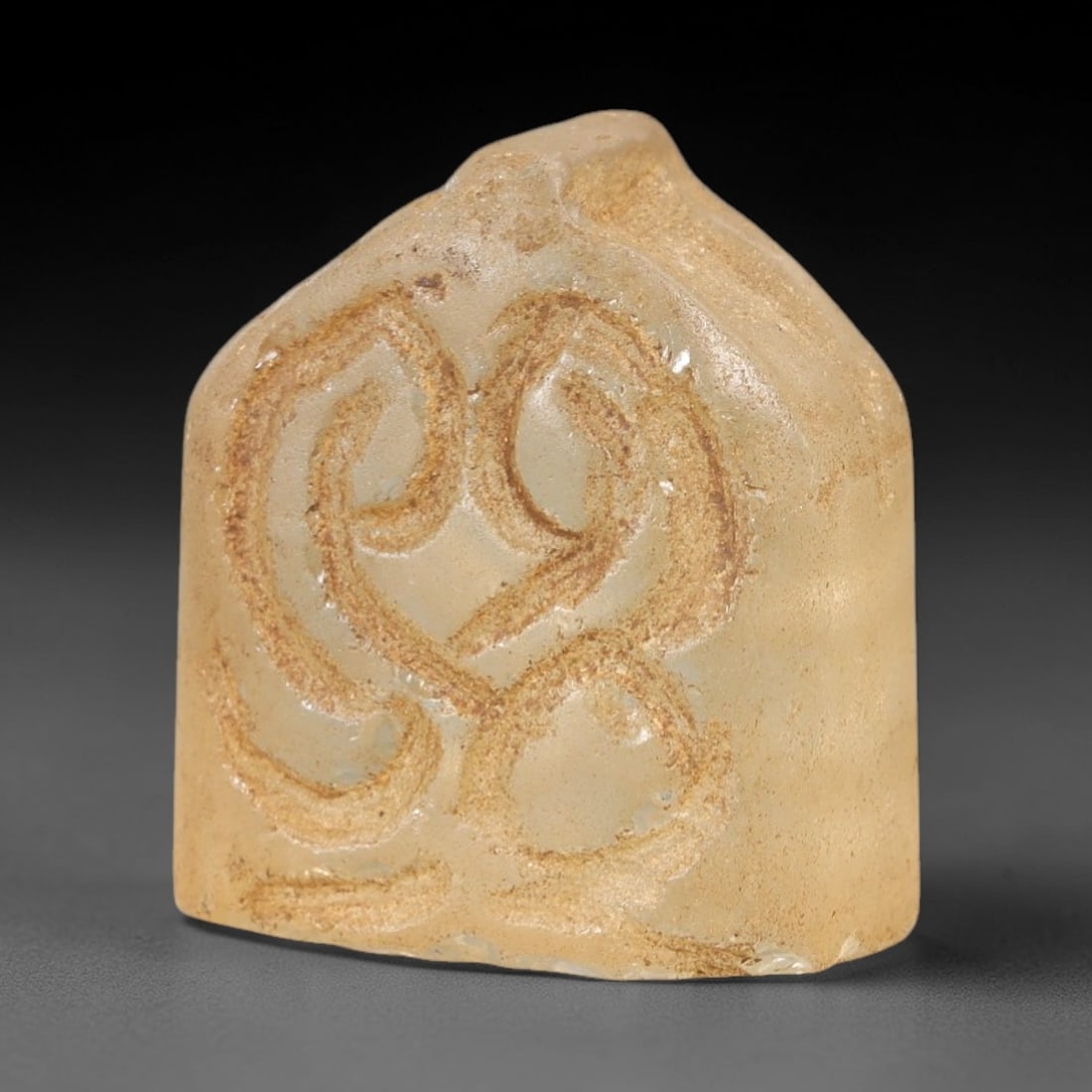 Ancient Rock Crystal Relic - Near Eastern Carving, 66AL: This artifact is carved from translucent rock crystal, featuring a compact, block-like form with incised curvilinear decorative motifs across its primary face. The carving exhibits simple, flowing lin