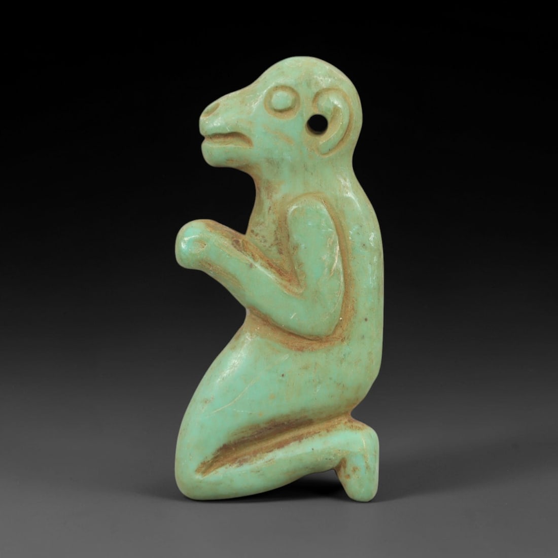 Ancient Turquoise Primate - Near Eastern Amulet Figurine, 80AK: Carved from polished turquoise, this amulet depicts a stylized kneeling primate figure with simplified facial features, a defined ear with suspension hole, and bent limbs in a prayerful or ritual pose