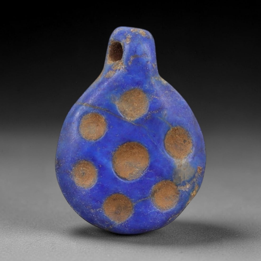 Ancient Lapis Lazuli Amulet - Egyptian Dot Pattern Pendant, 11AP: Carved from lapis lazuli, this amulet features a teardrop-shaped form with a drilled suspension hole piercing the upper lug, its surface decorated with evenly spaced recessed circular dot indentations