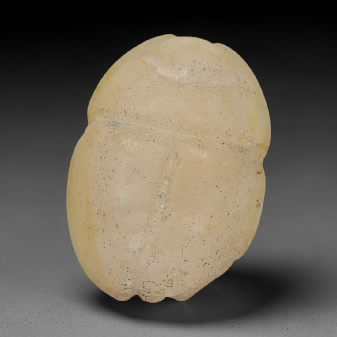 Ancient Chalcedony Scarab Amulet - Egyptian Figurine, 15AJ: Carved from smooth, pale yellow chalcedony with natural surface inclusions and subtle tonal variations, this amulet is formed as a stylized scarab beetle with incised linear detailing to define the ce
