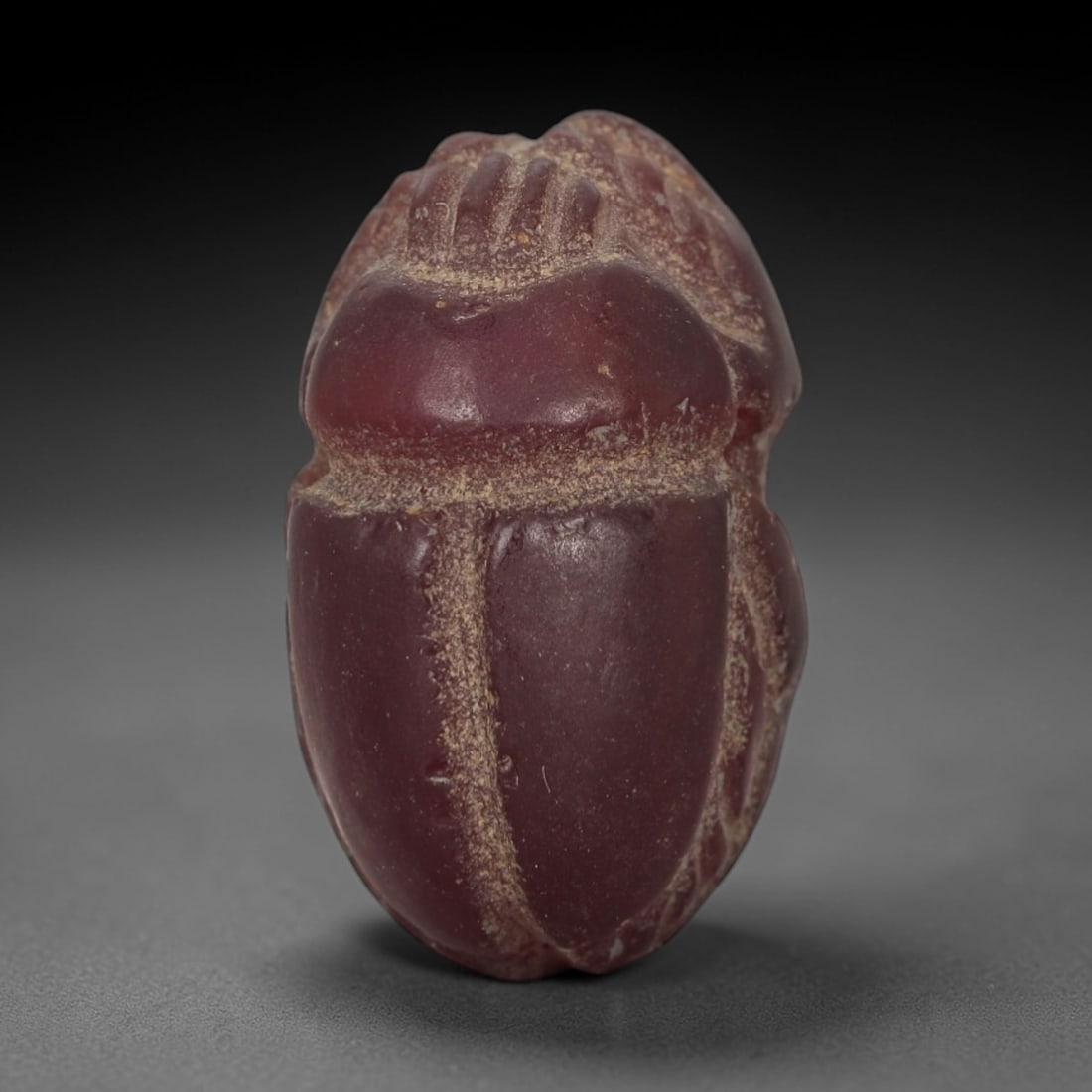 Ancient Red Jasper Scarab Amulet - Egyptian Figurine, 82AJ: Carved from deep, saturated red jasper, this amulet is formed as a stylized scarab beetle with incised linear detailing to define segmented head plates, central body ridge, and wing case contours, con