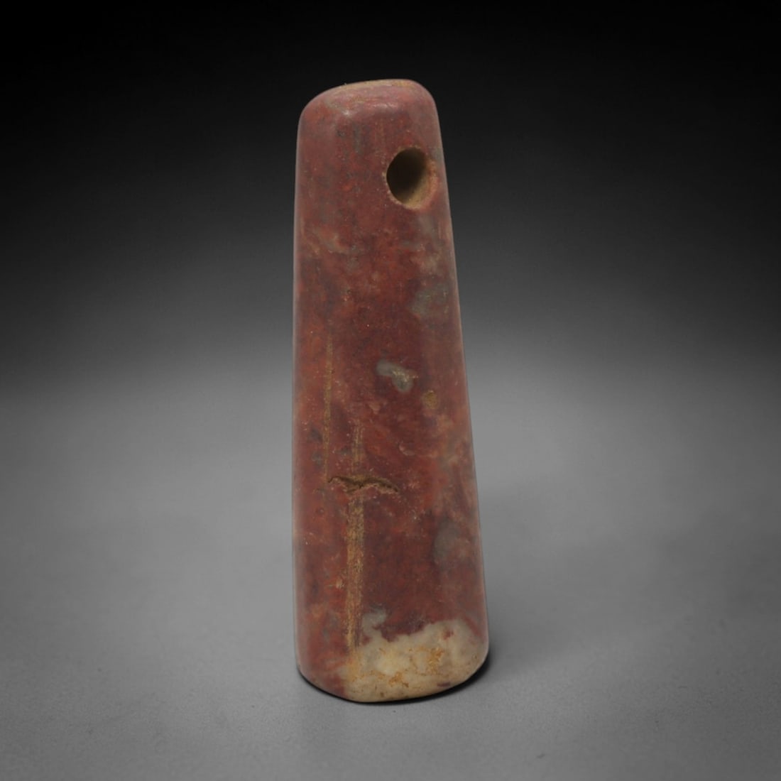 Ancient Stone Tapered Amulet - Near Eastern Pendant, 39XQ: Carved from a rich reddish stone with natural pale inclusions and subtle veining, this amulet takes a tall, tapered cylindrical form with a rounded top and flat base. A neatly drilled suspension hole