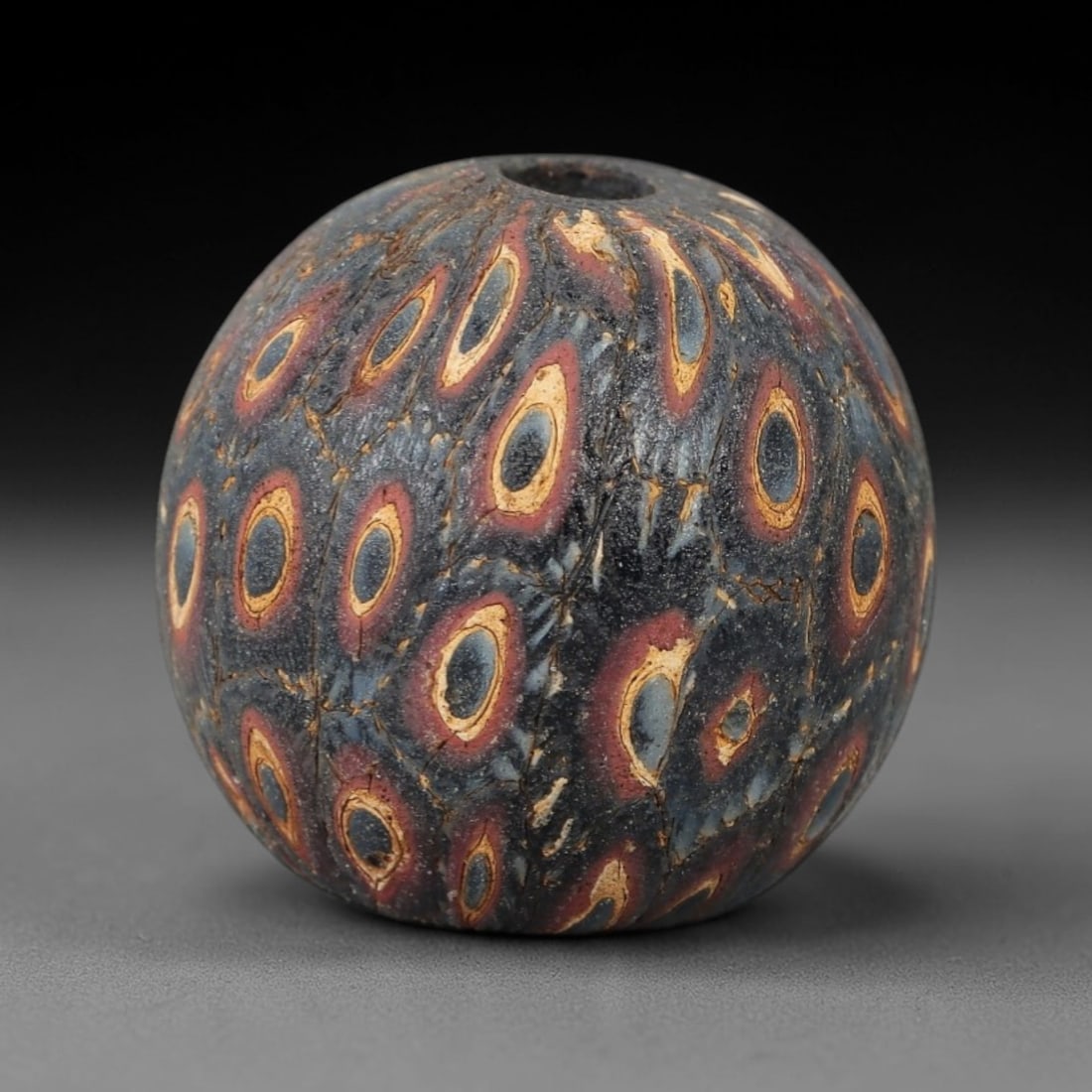 Ancient Glass Eye Bead - Egyptian Amulet Bead, 46ZM: This ancient bead is crafted from polychrome glass, formed using core-formed and trailed decorative techniques characteristic of Egyptian glassworking traditions. The spherical form features multiple