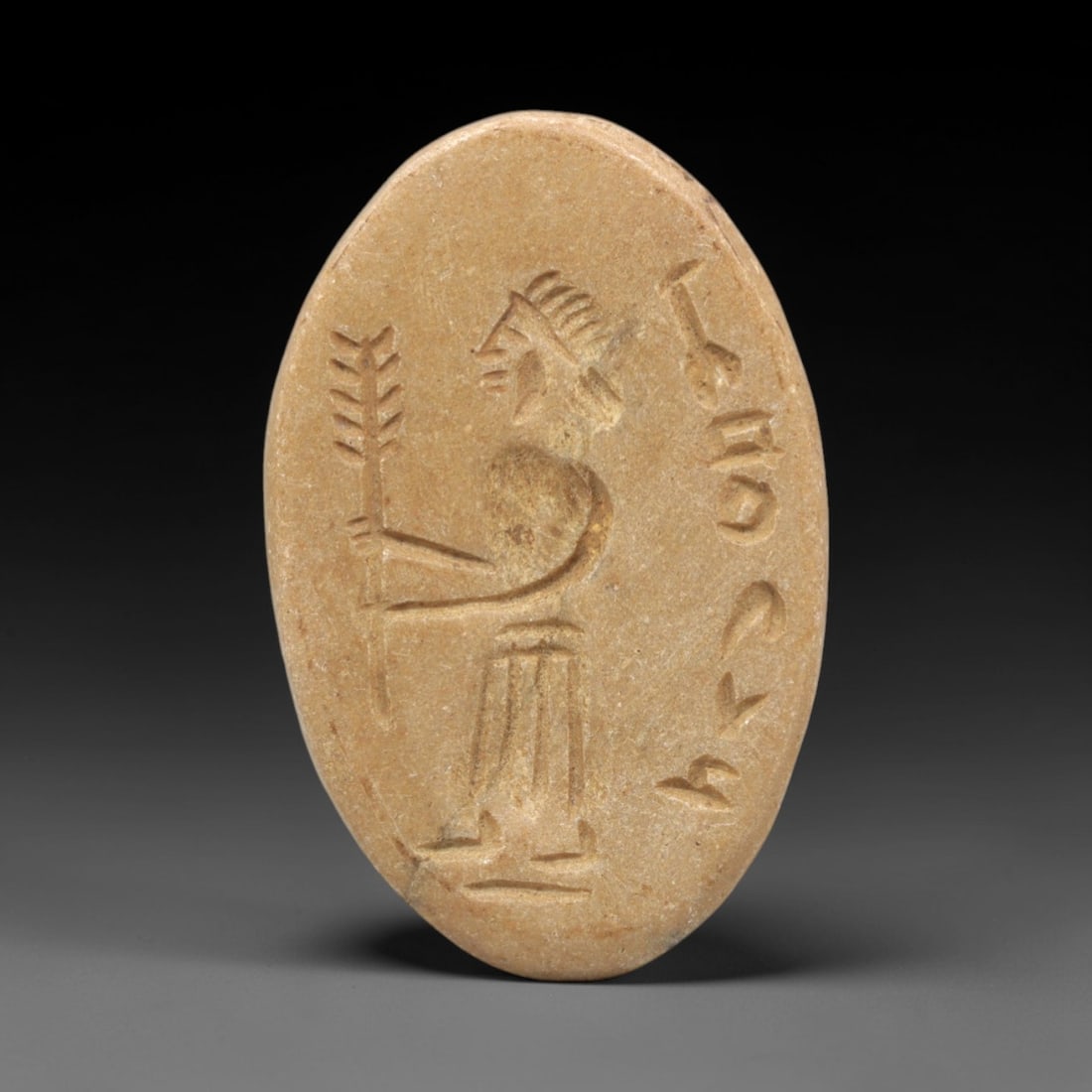 Ancient Stone Stamp Seal - Near Eastern Figurine, 26ZR: This artifact is an oval stone stamp seal, executed in the stylized anthropomorphic tradition of the ancient Near East. The seal's face depicts a standing figure holding a branch or staff, adorned wit