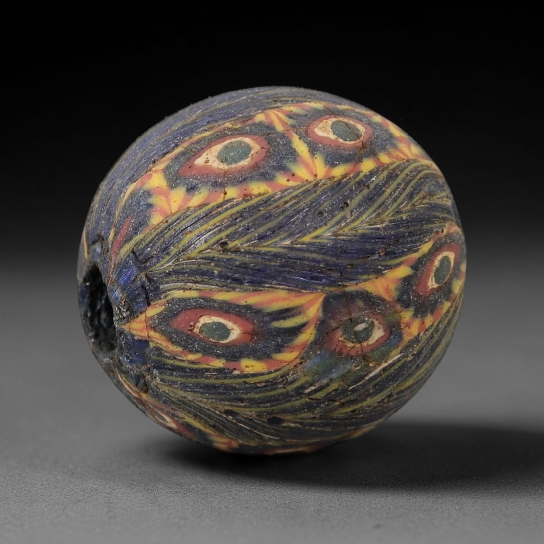Ancient Glass Eye Bead - Egyptian Amulet Bead, 52ZM: This ancient bead is crafted from polychrome glass, formed using core-formed and trailed decorative techniques characteristic of Egyptian glassworking traditions. The spherical form features multiple