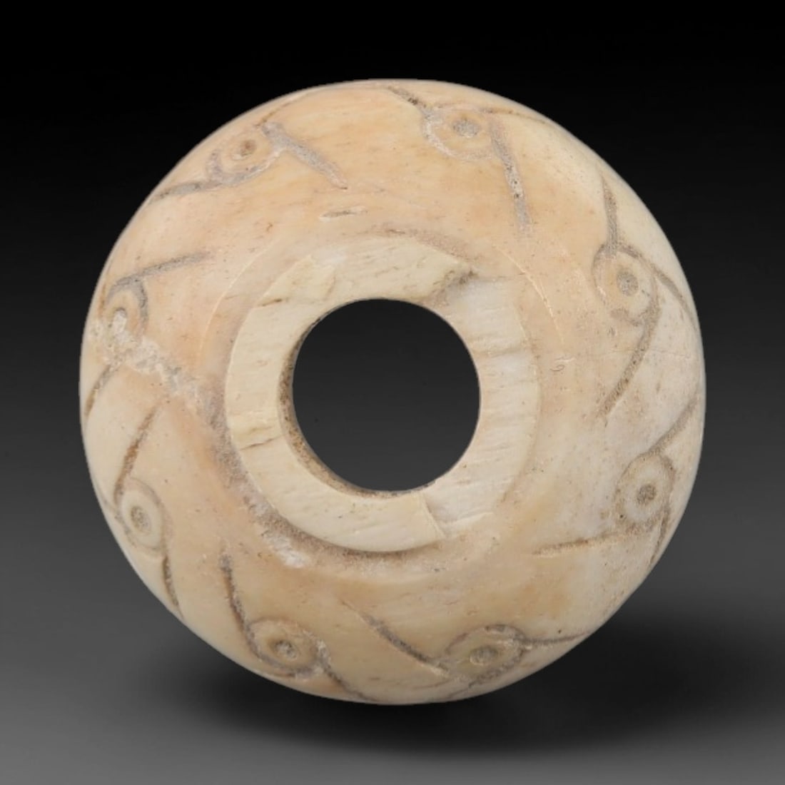 Ancient Near Eastern Bone Spindle Whorl - Dot-in-Circle Motif, 5AJ: Carved from ancient bone, this Near Eastern spindle whorl features a continuous dot-in-circle motif encircling its central perforation, a design with apotropaic significance in ancient Near Eastern cu