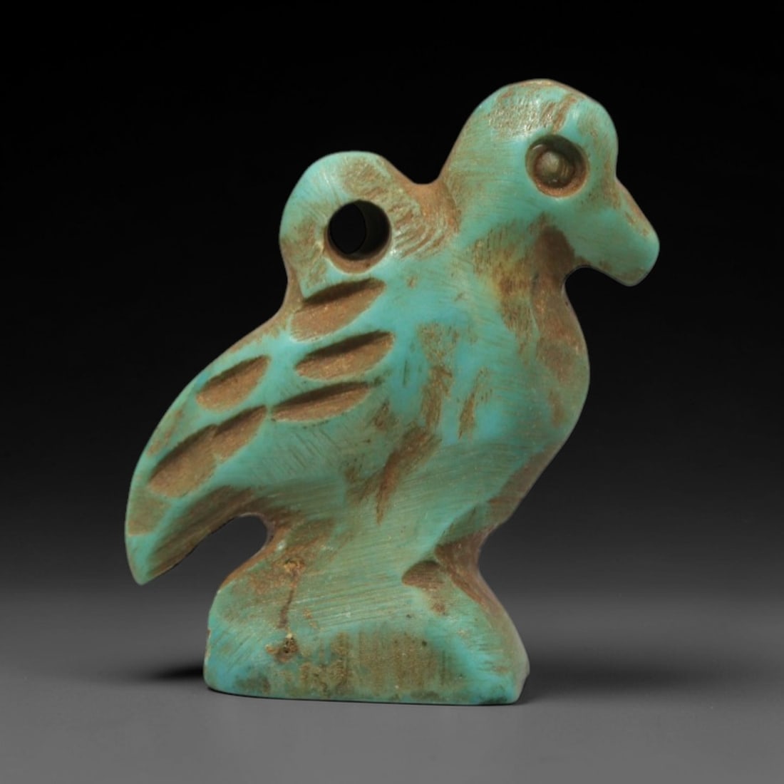 Ancient Turquoise Bird Amulet - Egyptian Animal Figurine, 5ZS: This artifact is a carved turquoise bird amulet, crafted in the stylized zoomorphic tradition of ancient Egypt. The amulet depicts a standing bird with simplified anatomical features, including a prom