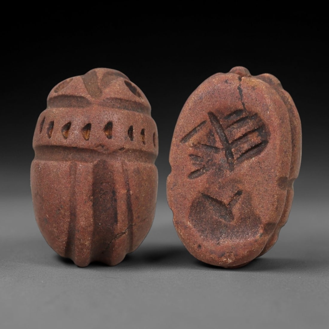 Ancient Steatite Scarab Stamp Seal - Near Eastern Linear Motif Figure, 73AM: Carved from reddish-brown steatite, this Near Eastern scarab stamp seal features a dorsal scarab pattern with incised linear elytra segments and decorative perforations, while the ventral face display
