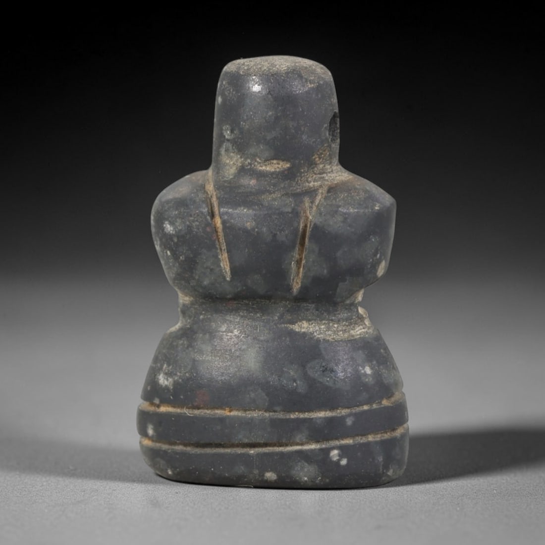 Ancient Stone Abstract Amulet - Near Eastern Figurine, 85AR: This artifact is carved from a dark, granular stone with a smooth, matte finish and subtle surface wear consistent with age. The form is an abstract anthropomorphic amulet, with a rounded head, broad