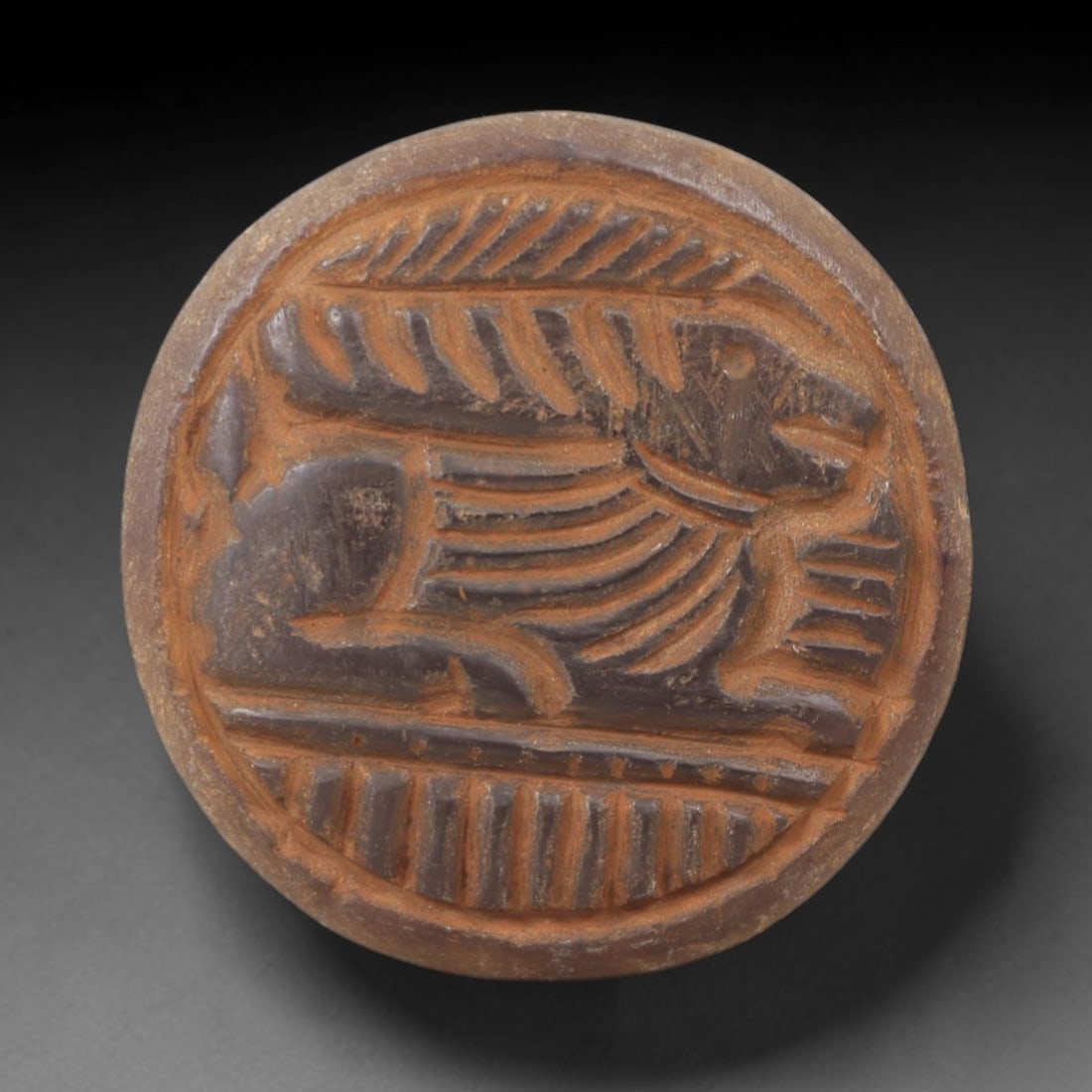 Ancient Chalcedony Plaque - Near Eastern Animal Relief, 99AK: Carved from chalcedony, this circular plaque features a low-relief scene depicting a stylized quadrupedal animal, likely a gazelle or ibex, with incised linear details defining the body, limbs, and a