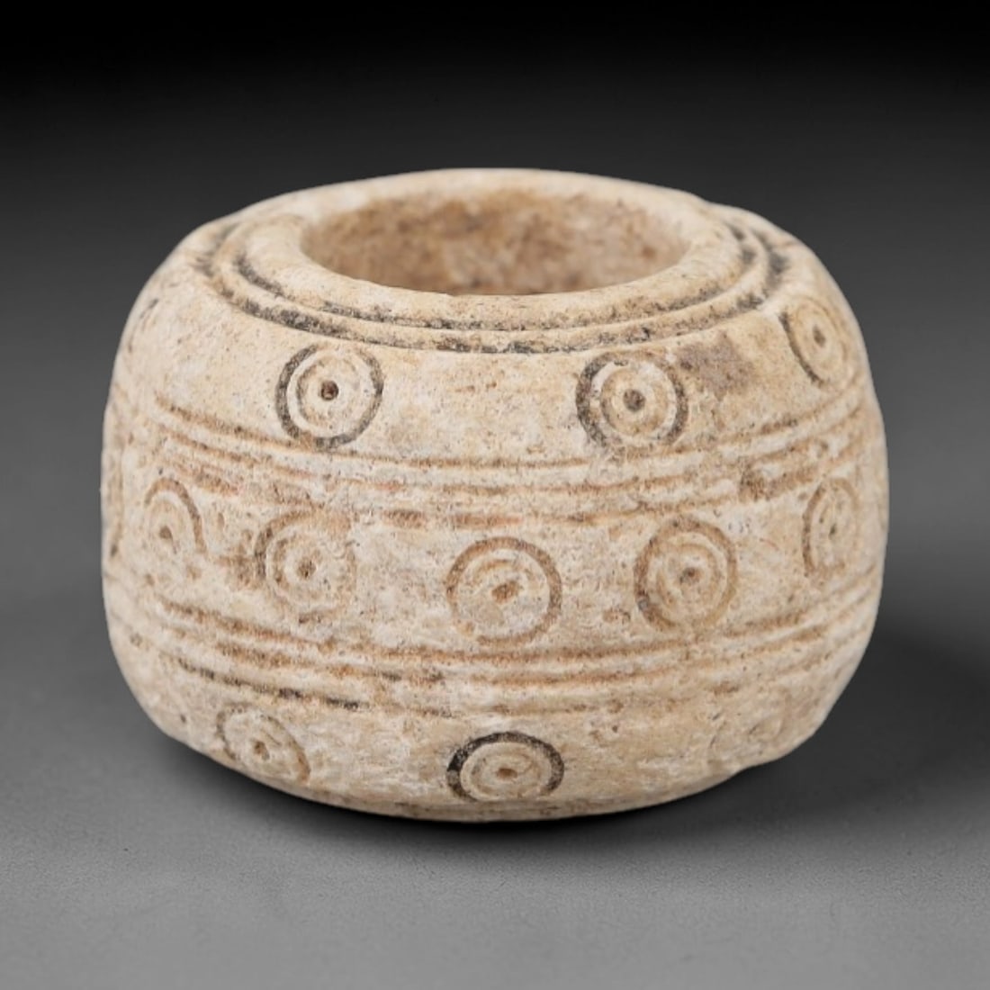 Ancient Near Eastern Bone Spindle Whorl - Dot-in-Circle Motif, 95AH: Carved from ancient bone, this Near Eastern spindle whorl features a continuous dot-in-circle motif encircling its central perforation, a design with apotropaic significance in ancient Near Eastern cu