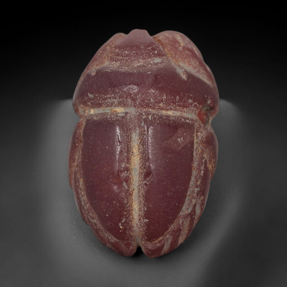 Ancient Red Jasper Scarab Amulet - Egyptian Figurine, 45AJ: Carved from deep, saturated red jasper, this amulet is formed as a stylized scarab beetle with incised linear detailing to define segmented body plates and distinct wing case contours, consistent with