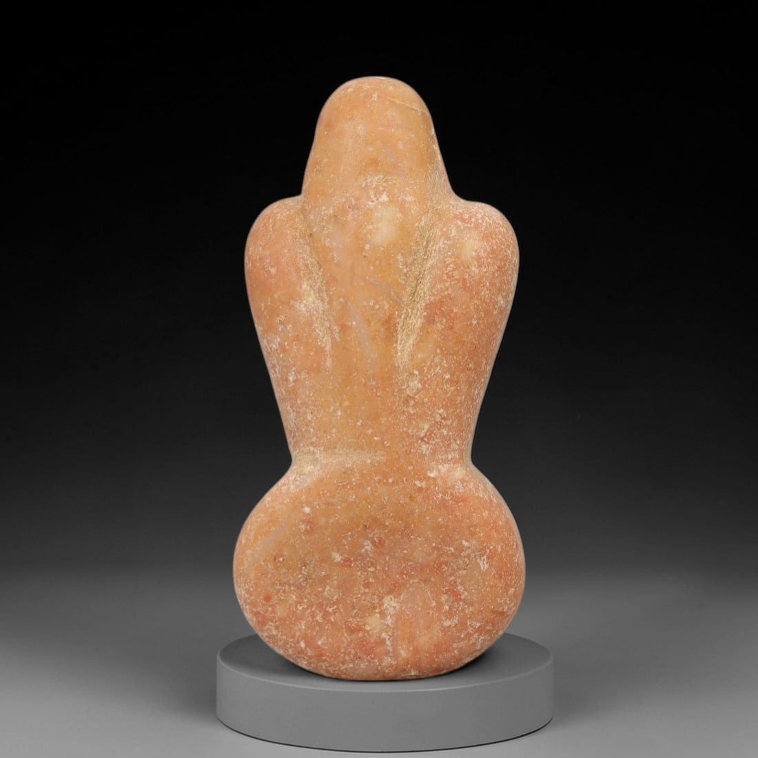 Ancient Peach Stone Fertility Idol - Near Eastern Figurine, 23AE: This artifact is a carved peach-toned stone fertility idol of Near Eastern origin, fashioned from a warm, ochre-hued stone with natural mineral inclusions and a powdery, aged patina. Its abstract anth