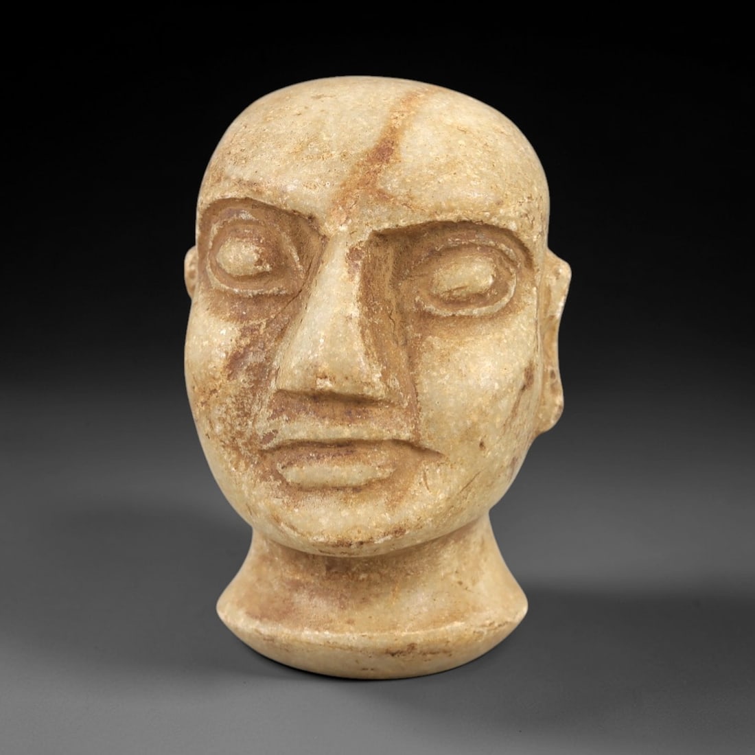 Ancient Stone Bactrian Idol Head - Central Asian Figurine, 82AL: Carved from pale tan limestone, this Bactrian idol head depicts a stylized anthropomorphic form with a smooth, rounded cranium, simplified ears, and deeply incised facial features including large roun