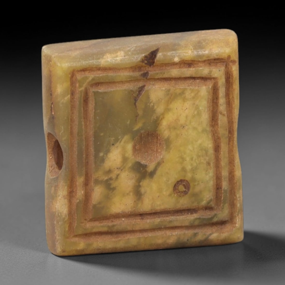 Ancient Serpentine Square Bead - Near Eastern Amulet, 89AK: Carved from serpentine, this square bead features a double incised square border framing a central raised boss and a smaller circular motif, with a lateral suspension hole for wearable use. Attributed
