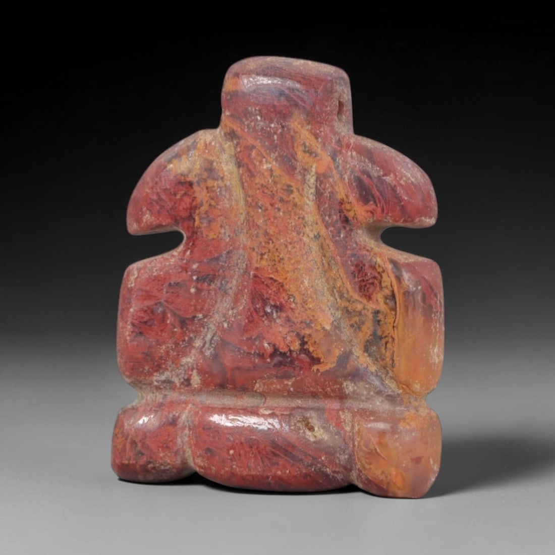 Ancient Jasper Bird Amulet - Near Eastern Figurine, 76AP: This artifact is carved from variegated red and orange jasper, exhibiting natural banding and mineral inclusions throughout its compact form. The stylized avian figure features a rounded head, simplif