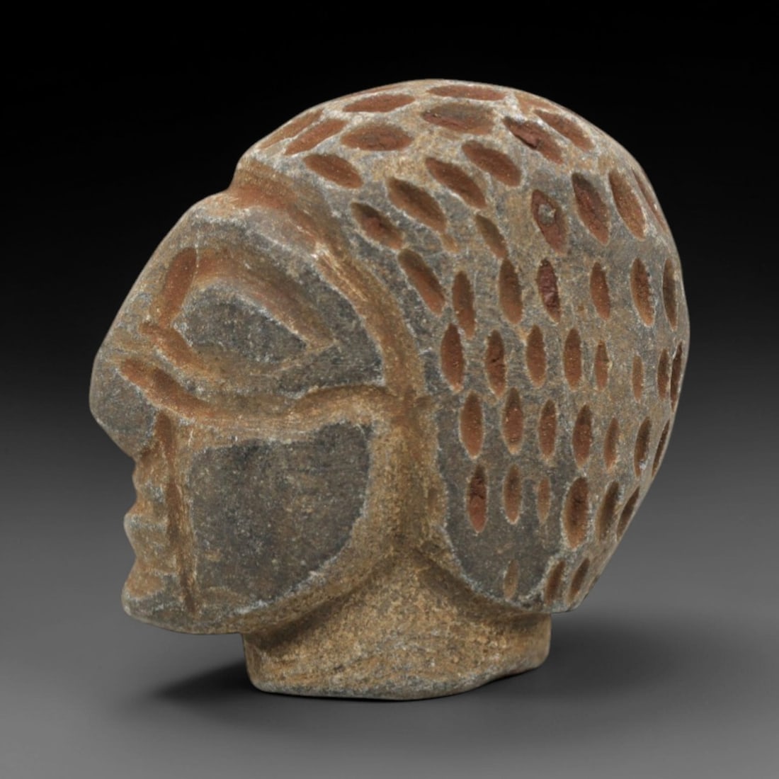 Ancient Stone Face Amulet - Near Eastern Anthropomorphic, 44ZR: Carved from dense grey-brown stone with subtle terracotta-hued patination, executed in a simplified yet expressive stylistic manner typical of early Near Eastern amuletic craftsmanship. The form prese