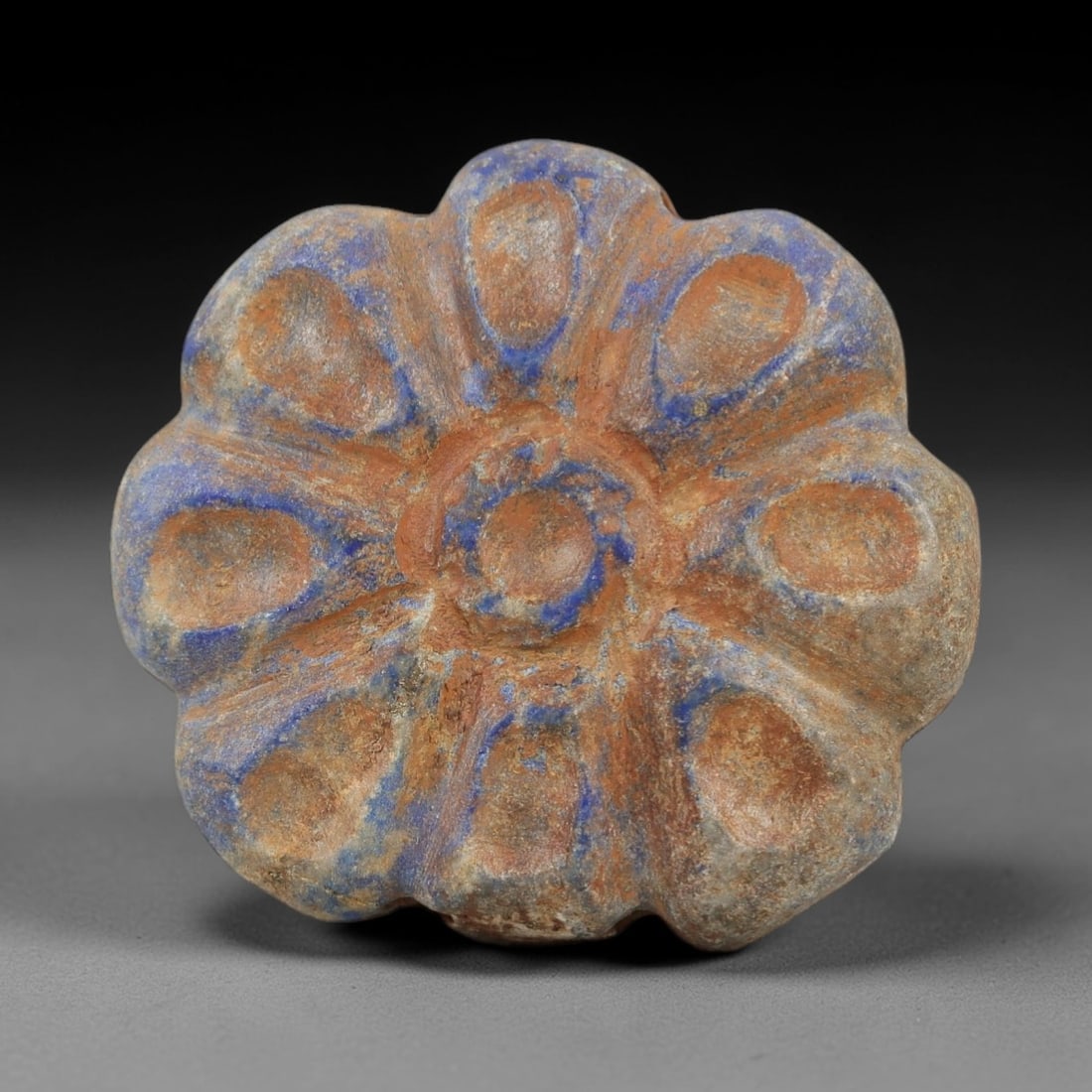 Ancient Lapis Lazuli Bead - Achaemenid Amulet, 6AH: Carved from lapis lazuli, this ancient Achaemenid bead features a scalloped, petal-like form with a central perforation, typical of Achaemenid Persian decorative and amuletic objects. The stone exhibi