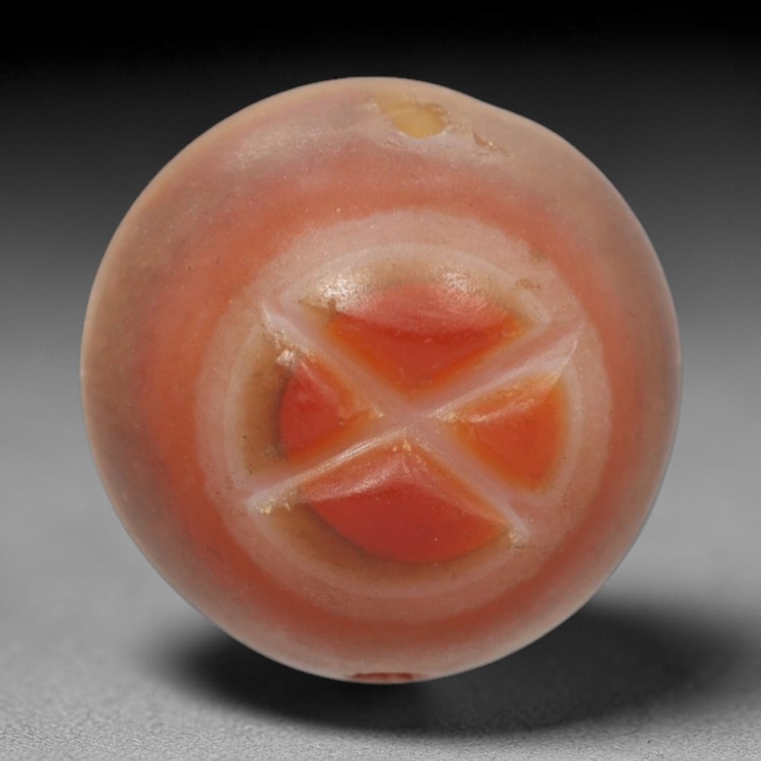 Antique Agate Bead - Central Asian, 21ZW: Crafted from banded agate, this spherical bead exhibits the characteristic lapidary work of antique Central Asian jewelry. Its surface features a recessed geometric cross motif, carved into the centra
