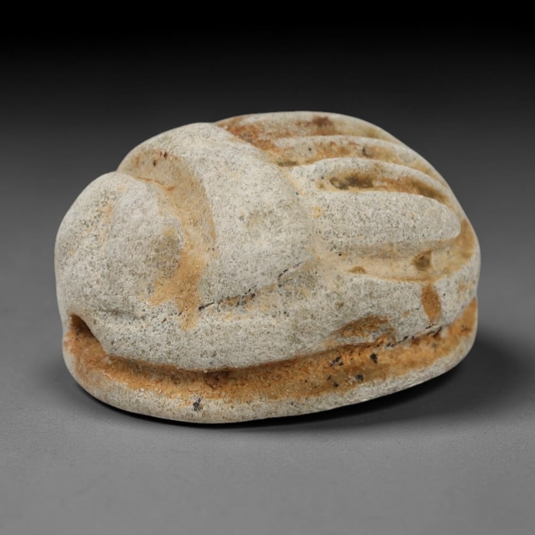An Ancient Near Eastern Stone Scarab Stamp Seal, 1st Millennium BCE, 5ZM: Carved from pale, granular stone with natural surface patination and subtle tonal variation, the object is formed as an oval scarab seal. The dorsal side is modeled in low relief with a segmented cara