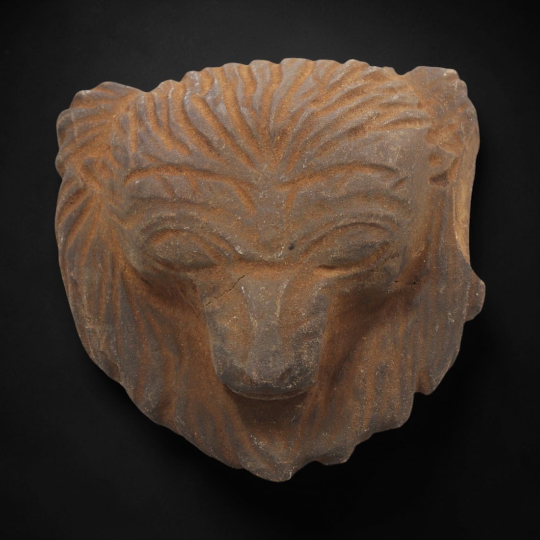 Ancient Stone Feline Head - African Tribal Artifact, 35FX: Carved from a dense, earthy-brown stone with a rich, rust-toned patina, this artifact depicts a stylized feline head in high relief, characterized by a full, radiating mane rendered with incised linea