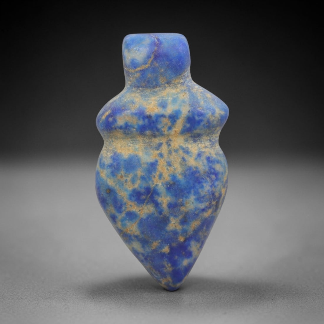 Ancient Lapis Lazuli Heart Amulet - Egyptian Ritual Pendant, 22ZT: Carved from lapis lazuli, this amulet features a stylized heart form with a cylindrical upper lug pierced for suspension, its body defined by a subtle raised collar at the shoulder and tapering to a s