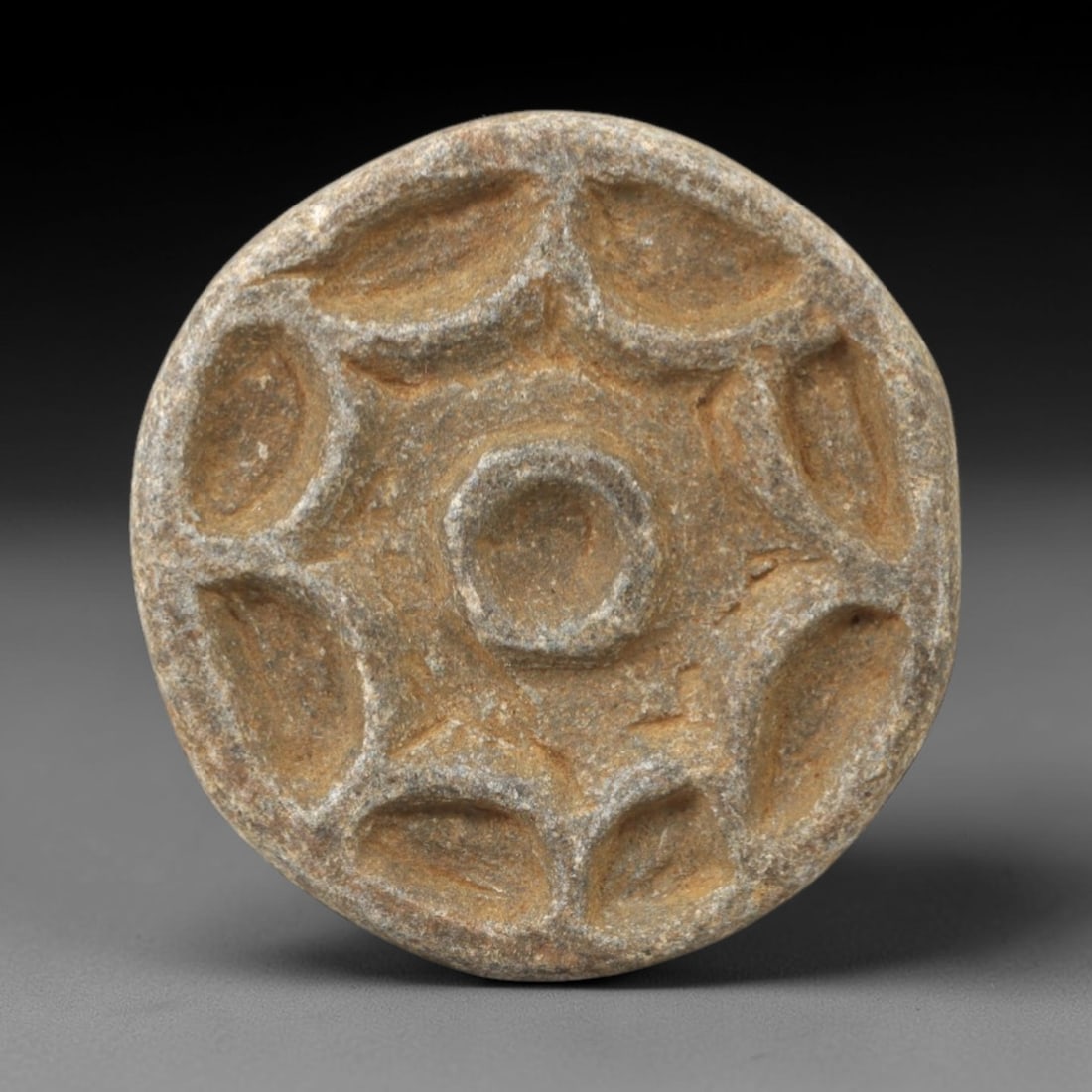 Ancient Steatite Rosette Stamp Seal - Near Eastern Amulet, 92AK: Carved from steatite, this circular stamp seal features a central raised boss surrounded by six incised, petal-shaped motifs forming a symmetrical rosette design. The flat base is intended for impress