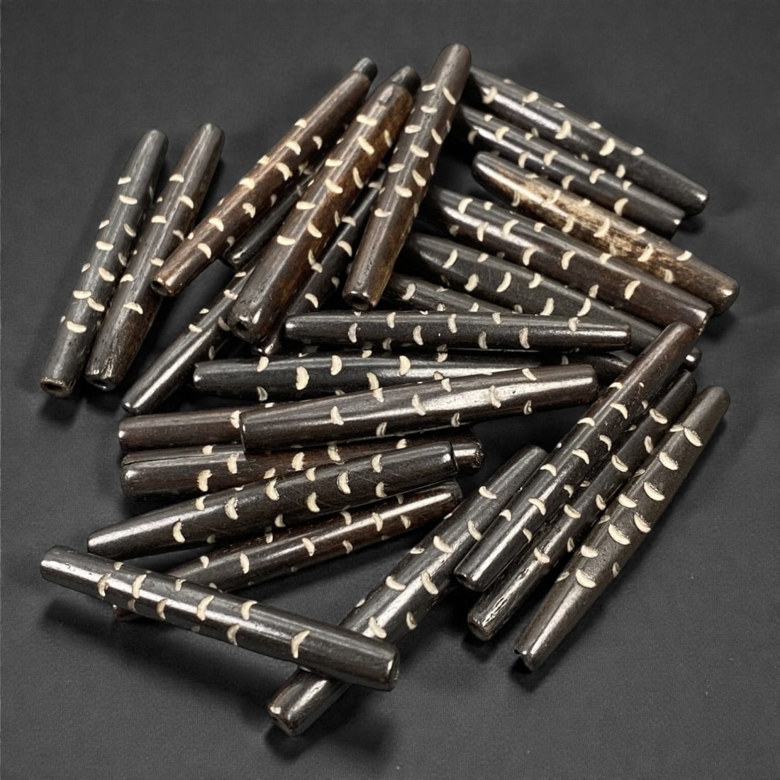 A Tibetan Bone Bead Group, Inlaid Linear Dot Pattern, 20th Century, 97S: Composed of animal bone, each bead features an elongated cylindrical form with consistent length and diameter across the group. The surface displays an inlaid linear dot pattern, with small white inla