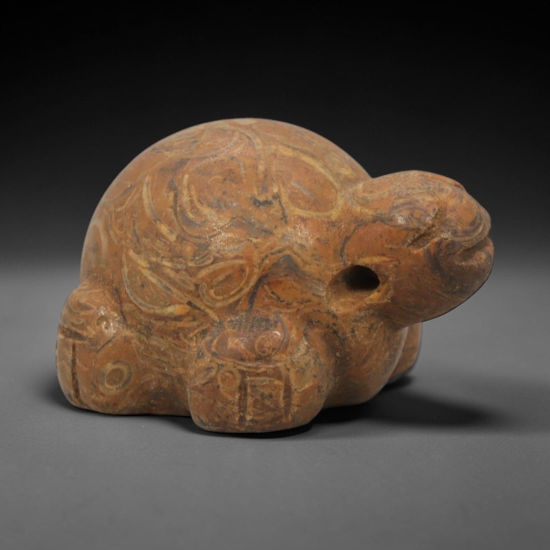 Ancient Stone Turtle Amulet - Egyptian Pendant, 76XQ: Carved from a warm, banded orange-brown stone, this amulet depicts a stylized recumbent turtle with intricate incised swirling patterns across its domed shell and limbs, evoking the natural texture of