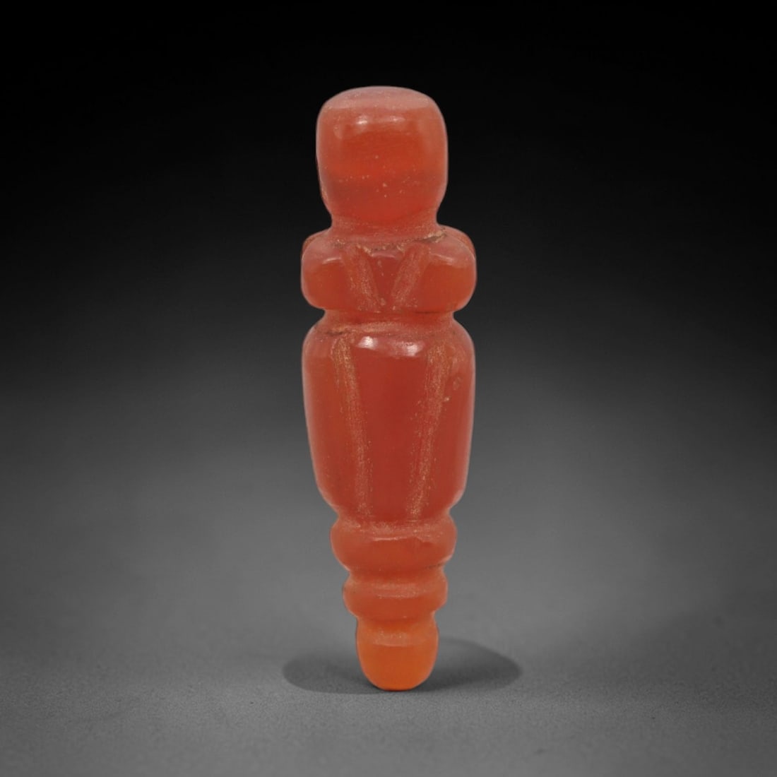 Ancient Carnelian Tyet - Egyptian Amulet Figurine, 72XS: Carved from rich, translucent carnelian with subtle surface wear and residual incised lines, this amulet takes the form of a stylized tyet (Isis knot), a sacred Egyptian symbol of protection and ferti