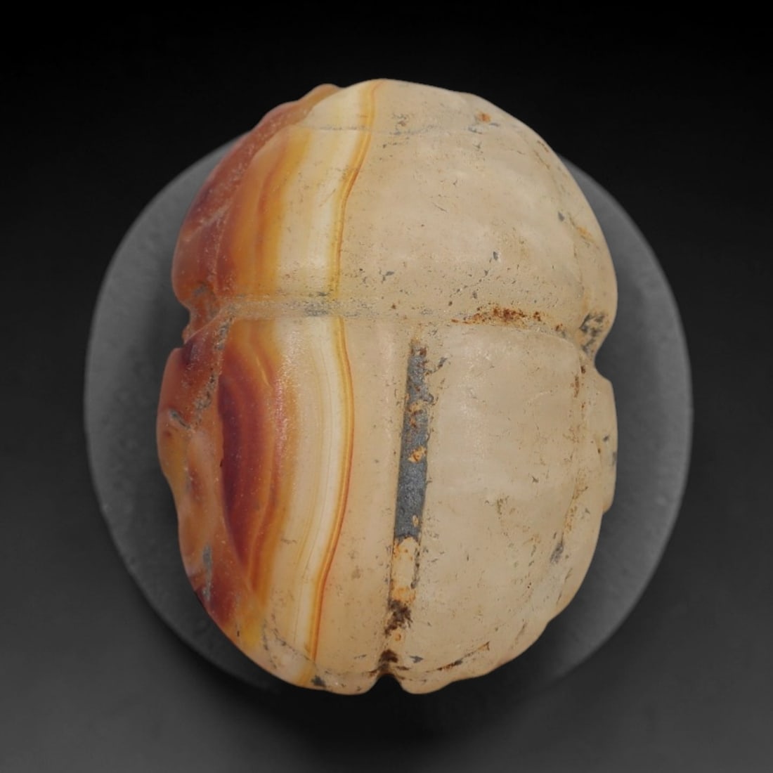 Ancient Banded Agate Scarab Amulet - Egyptian Figurine, 79AJ: Carved from striking banded agate with alternating creamy white and warm orange-red concentric layers, this amulet is formed as a stylized scarab beetle with subtle linear detailing to define segmente