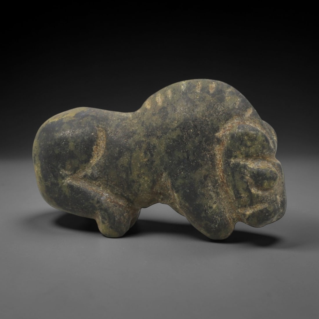 Ancient Green Stone Lion - Near Eastern Zoomorphic Figurine, 77XP: Carved from a mottled green stone, this miniature zoomorphic figurine depicts a stylized lion in a recumbent pose, a powerful motif in ancient Near Eastern iconography symbolizing royal authority and