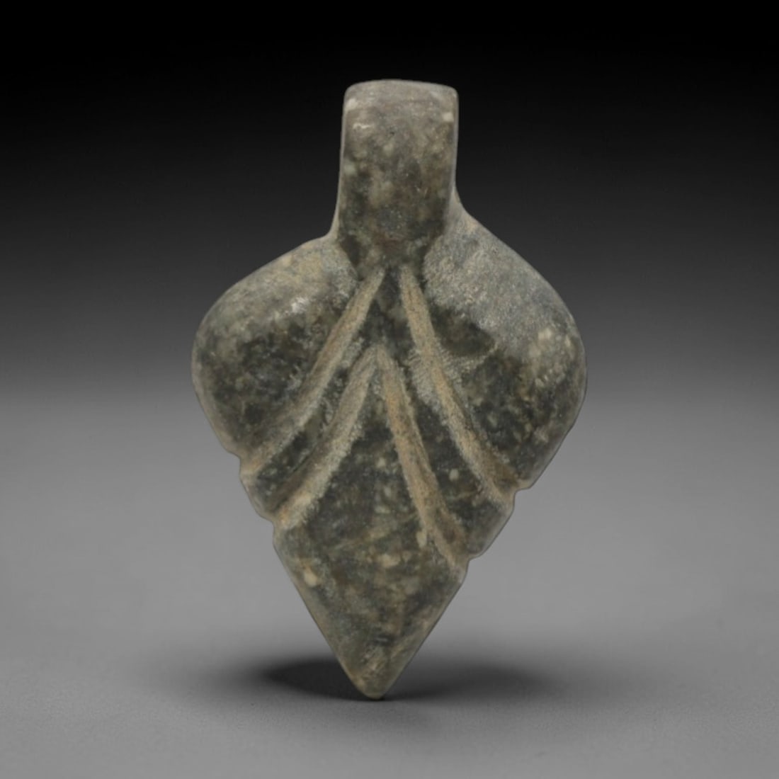 Ancient Stone Leaf Amulet - Near Eastern Pendant, 68XQ: Carved from a mottled grey-green stone, this amulet takes a stylized leaf form with incised central and lateral veins, topped by a small suspension tab for wearable use. The form and vegetal decoratio
