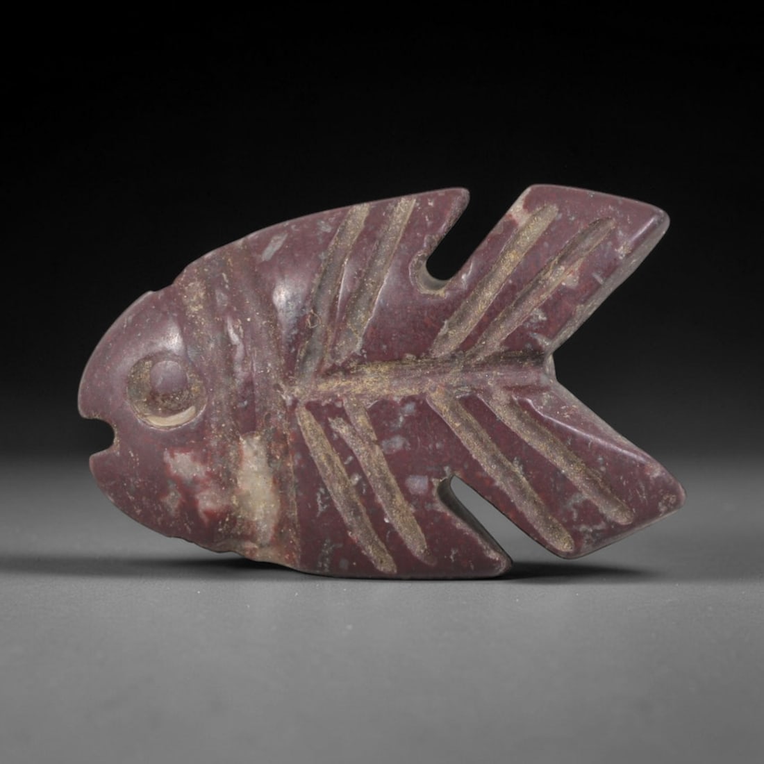 Ancient Stone Fish - Egyptian Amulet Figurine, 40AP: This artifact is carved from deep red stone with a weathered, earthy patina and subtle mineral inclusions, exhibiting incised skeletal fin detailing consistent with ancient Egyptian stoneworking techn