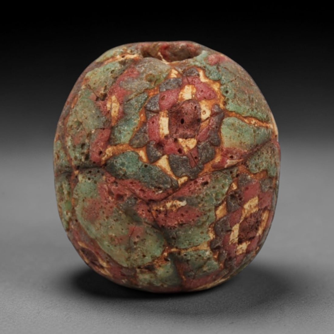 Ancient Glass Bead - Roman Egyptian Mosaic Amulet, 59ZN: Crafted from mosaic glass, this ovoid bead features a central suspension hole and is decorated with intricate geometric floral motifs in green, red, cream, and dark grey glass inlay, characteristic of