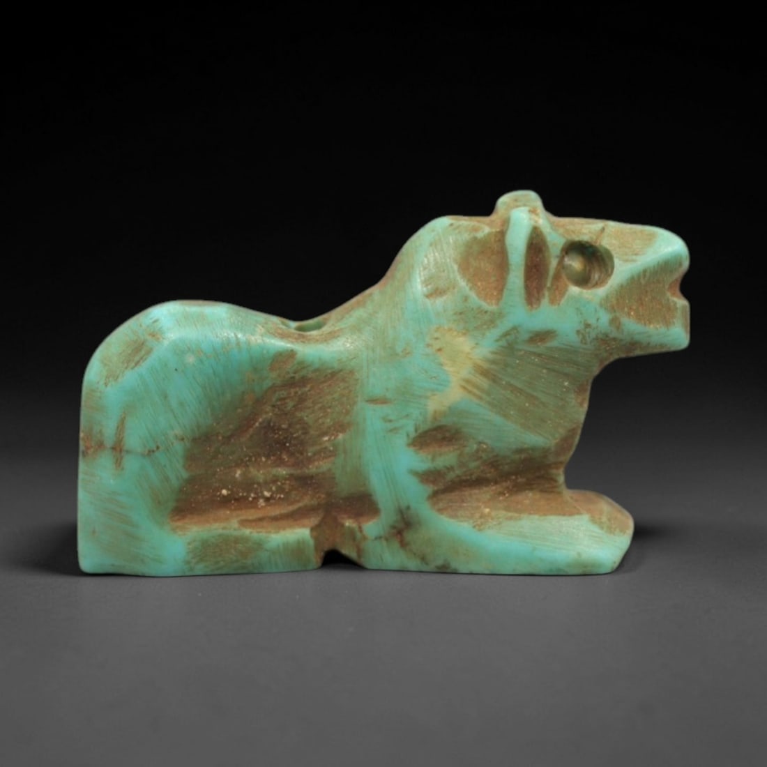 Ancient Turquoise Feline Amulet - Egyptian Animal Figurine, 23ZS: This artifact is a carved turquoise feline amulet, crafted in the stylized zoomorphic tradition of ancient Egypt. The amulet depicts a recumbent feline with simplified anatomical features, including a