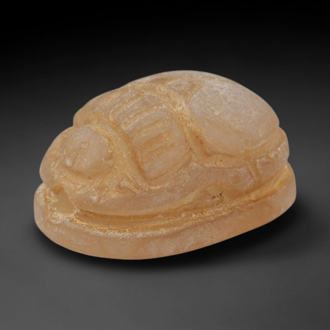 An Ancient Near Eastern Chalcedony Scarab Stamp Seal, 1st Millennium BCE, 1ZM: Carved from translucent chalcedony with a pale, milky patina and subtle internal veining, the object is formed as an oval scarab seal. The dorsal side is modeled in low relief with a segmented carapac
