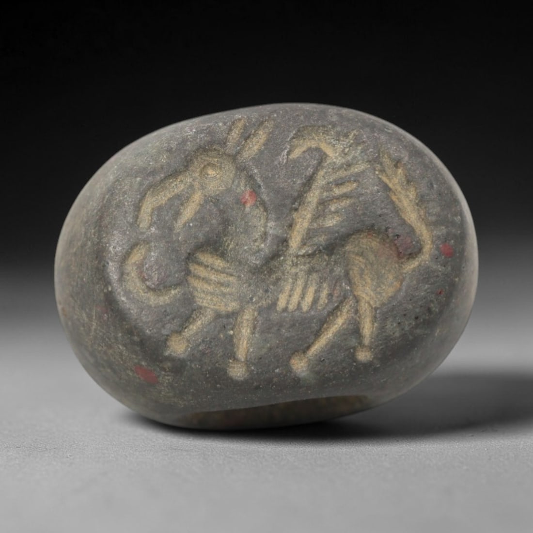 Ancient Stone Hemispherical Stamp Seal - Near Eastern Mythical Hybrid Figure, 97ZS: Crafted from dense, dark gray stone, this hemispherical stamp seal bears incised carving of a mythical hybrid creature, likely a winged equine or chimera, with a stylized equine head, elongated snout,